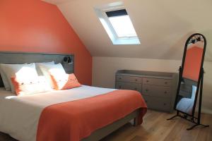 een slaapkamer met een bed met een oranje muur bij Ti Mein Glas, maison proche de Quimper in Landudal