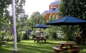 two picnic tables with umbrellas in a park at Prästgården Hotell & Bryggeri in Söderhamn