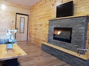 a living room with a stone fireplace with a flat screen tv at Schoolhouse Inn in Killaloe Station