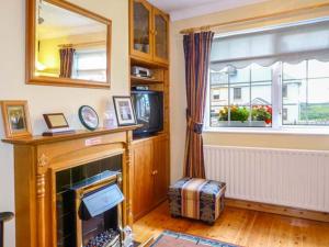 sala de estar con chimenea y ventana en Village Cottage en Dunkineely