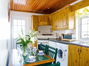a kitchen with a table with chairs and a washing machine at Village Cottage in Dunkineely