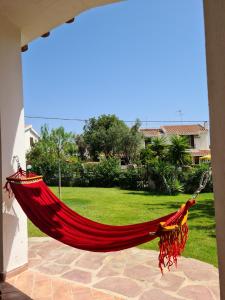 een rode hangmat op een patio met een tuin bij Casa vacanze 'Sa Corbula' in Porto Columbu - Perdʼe Sali