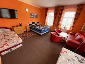 een slaapkamer met oranje muren en een bed en stoelen bij Penzion Villa Rosse in Abertamy