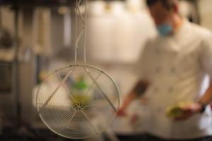 a strainer hanging in a kitchen with a person in the background at Hotel Zeni in Brentonico