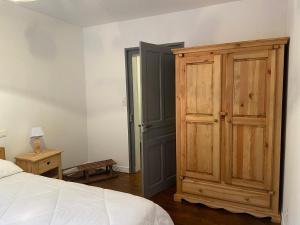 a bedroom with a wooden cabinet next to a bed at Le Chellois appartement La Bresse in La Bresse