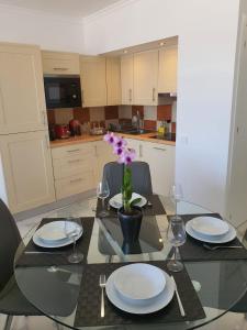a dining table with plates and glasses and a flower on it at T0 Vilamoura Downtown in Vilamoura