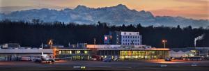 un avion garé dans un aéroport avec des montagnes en arrière-plan dans l'établissement ibis Hotel Friedrichshafen Airport Messe, à Friedrichshafen