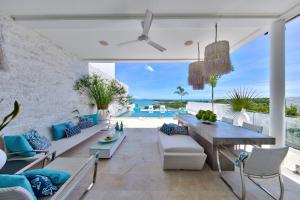 a living room with a dining table and a view of the ocean at BEACHSIDE VILLA - LATITUDE 9 - at BAYSIDE LUXURY VILLAS Samrong Bay Beach, 3 BED 4 BATH, SEA and SUNSET VIEWS, only 200m walk to the Beach in Thong Son Beach