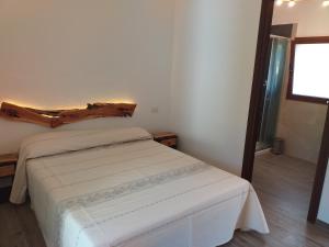 a bedroom with a white bed with a wooden headboard at Turismo Rurale Lu Stazzu Arzachena in Arzachena