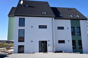 a white building with a black roof at Apartment Aurachtal Münchaurach in Falkendorf