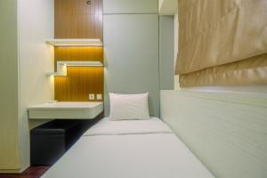 a small room with a bed and a desk at New Furnished and Minimalist 3BR at Meikarta Apartment By Travelio in Cikarang