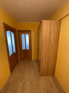 an empty room with two doors and wooden floors at Apes ielas apartaments in Alūksne