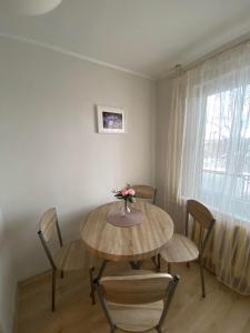 a dining room table with chairs and a vase of flowers on it at Apes ielas apartaments in Alūksne