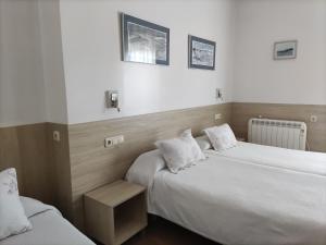 2 camas en una habitación de hotel con sábanas blancas en Pensión Atxiki, en San Sebastián