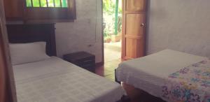 a room with two beds and a door with a window at Mi Ranchito, Centro in Barichara