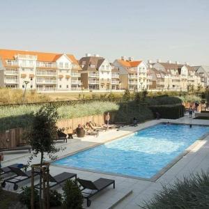 a large swimming pool with chairs and buildings in the background at Duplex Villa Capricia appartement met zwembad Nieuwpoort Jachthaven in Nieuwpoort