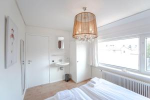 - une chambre blanche avec un lit et un lustre dans l'établissement Sea Star Stay with Private Parking!, à Zandvoort
