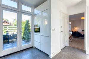 ザントフォールトにあるCasa Vos Family Homeの白いキャビネットとガラスの引き戸付きのキッチン