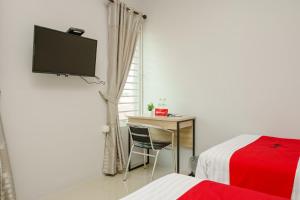 a bedroom with a bed and a desk and a television at RedDoorz @ Jalan Demang Lebar Raya Palembang in Palembang