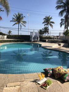 a swimming pool with drinks and fruit on the ground at Pousada Tortugas in Guarujá
