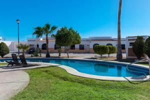 a swimming pool with palm trees and a building at Mexican Ambience Townhome with Pool #2 in Puerto Peñasco