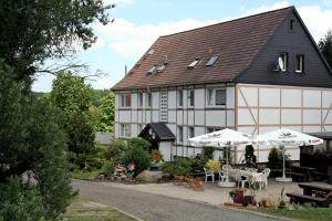 a large white and black building with tables and umbrellas at Pension Harzbaude Susanne - Garni in Rübeland