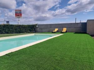 two chairs sitting next to a swimming pool with green grass at Casa São Simão in Barcelos