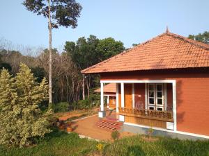 a small red house with a porch and a balcony at Tranquil Farms in Manimala