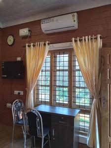 a kitchen with a desk and two chairs and windows at Tranquil Farms in Manimala