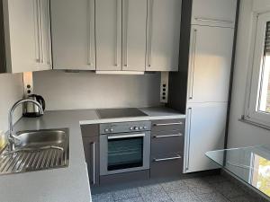 uma cozinha com armários brancos e um forno de aço inoxidável em Sky Night Suite em Düren - Eifel