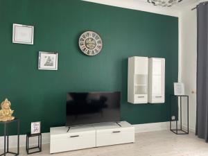 sala de estar con TV y pared verde en Sky Night Suite, en Düren - Eifel