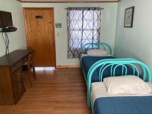 a room with two beds and a desk and a window at Hillside Motel in Lake George