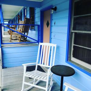 een schommelstoel en een tafel op de veranda van een huis bij Hillside Motel in Lake George