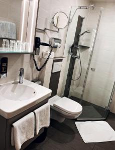 uma casa de banho com um chuveiro, um WC e um lavatório. em Hotel Paintner em Germering