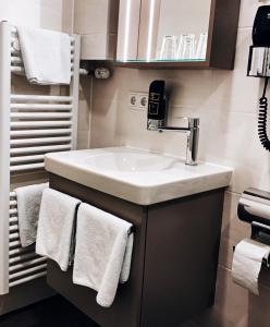 uma casa de banho com um lavatório branco e toalhas em Hotel Paintner em Germering