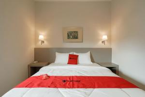 - une chambre avec un oreiller rouge sur un lit blanc dans l'établissement RedDoorz Syariah Plus @ BSD City, à Cilalung