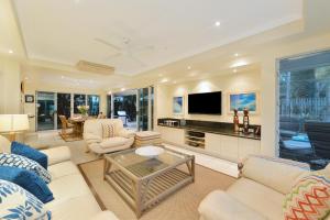 sala de estar con muebles blancos y TV de pantalla plana en Reef Villa Port Douglas, en Port Douglas