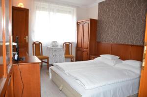 A bed or beds in a room at Szieszta Panzió