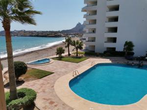 a swimming pool next to a building and the beach at Condominios San Carlos in San Carlos