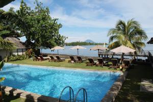 a swimming pool with chairs and umbrellas next to the water at Cocotinos Manado in Manado