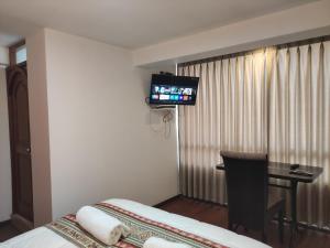 a hotel room with a bed and a flat screen tv at Casa del Escultor in Cusco