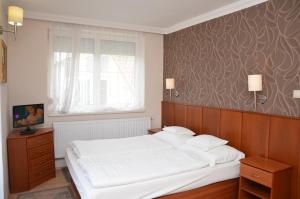 a bedroom with a large white bed and a window at Szieszta Panzió in Sárvár +11 photos