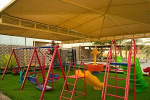 um parque infantil com balanços coloridos e um guarda-chuva em Elaf Resort 4 Bed room luxury resort em Al Muladdah