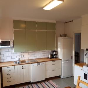 eine Küche mit weißen Schränken, einer Spüle und einem Kühlschrank in der Unterkunft Rumskulla guesthouse in Vimmerby