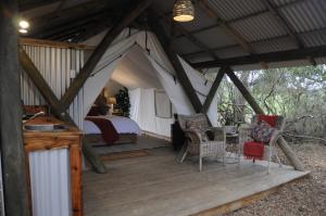 Zelt mit einem Bett und Stühlen auf einer Holzterrasse in der Unterkunft Heritage Glamping, Woodlands tent in Wilderness