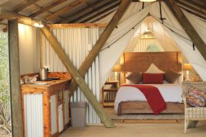 een slaapkamer in een tent met een bed en een bureau bij Heritage Glamping, Woodlands tent in Wilderness
