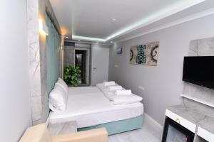 a living room with white furniture and a flat screen tv at Little sofia hotel in Istanbul