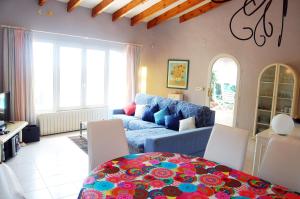 een woonkamer met een blauwe bank en een tafel bij CASA VIDA, villa encantadora con vistas al mar in Benitachell