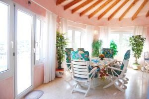 een eetkamer met een tafel, stoelen en ramen bij CASA VIDA, villa encantadora con vistas al mar in Benitachell