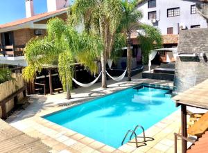里奧格蘭德的住宿－Lira Hotel & Restaurante，一个带吊床和棕榈树的游泳池